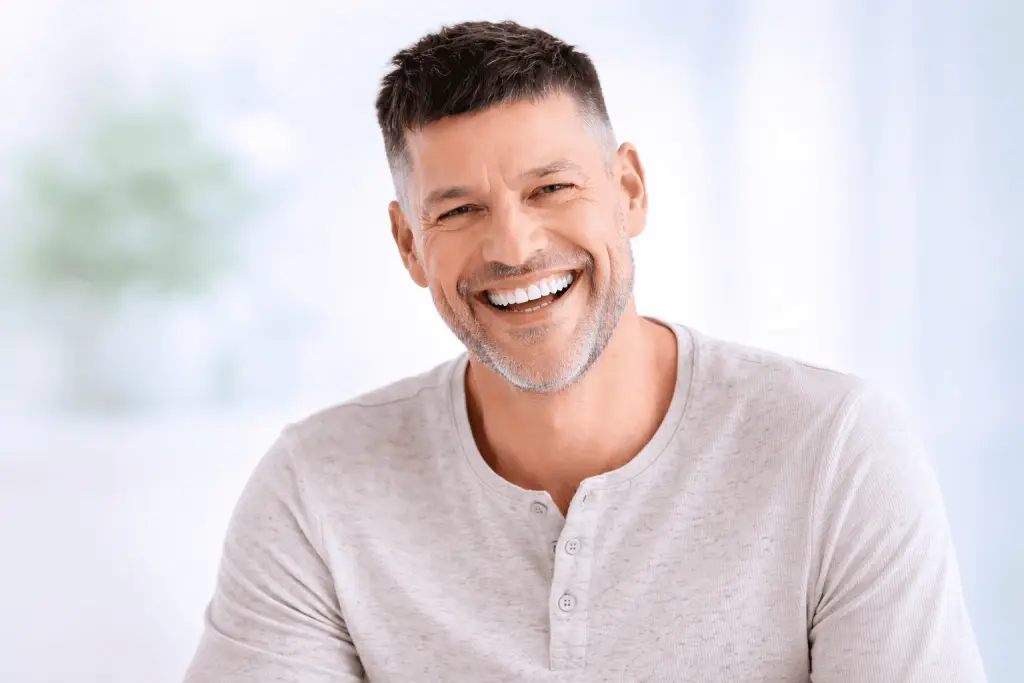 Homme souriant avec prothèse dentaire fixe à Lausanne, résultat stable et naturel proche de dents naturelles