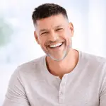 Homme souriant avec prothèse dentaire fixe à Lausanne, résultat stable et naturel proche de dents naturelles